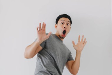 Gri tişörtlü Asyalı adam beyaz arka planda izole edilmiş..