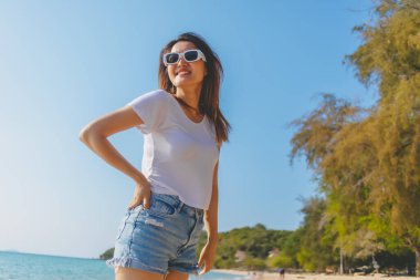 Mutlu Asyalı kadın güneşli sahilde fotoğraf çekmekten hoşlanıyor. Tayland.