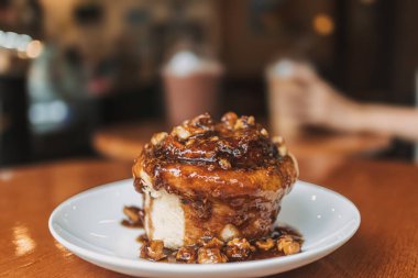 Kafedeki ahşap masada servis edilen karamelli çörek fırını tatlısı..