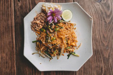 Mor çiçeklerle süslenmiş Pad Thai yemeğinin lüks görünümünün üstünde.