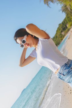 Mutlu Asyalı kadın güneşli sahilde fotoğraf çekmekten hoşlanıyor. Tayland.