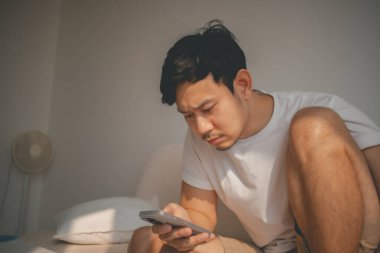 Cep telefonunun sosyal medyasına bakan depresif Asyalı adamı kapat..