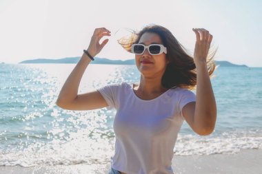 Mutlu Asyalı kadın güneşli sahilde fotoğraf çekmekten hoşlanıyor. Tayland.