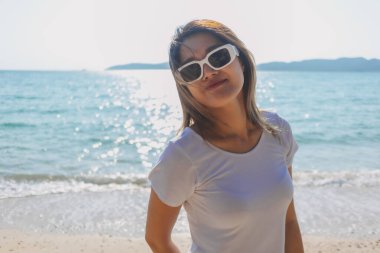 Mutlu Asyalı kadın güneşli sahilde fotoğraf çekmekten hoşlanıyor. Tayland.