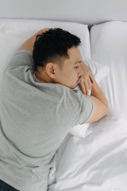 Ciddi ve depresif Asyalı adam yatakta yatan sorunları çok düşünüyor..