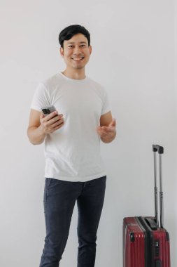 Evrak çantasıyla mutlu Asyalı adam cep telefonu standı kullanıyor..