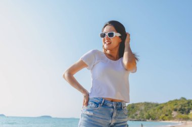 Mutlu Asyalı kadın güneşli sahilde fotoğraf çekmekten hoşlanıyor. Tayland.