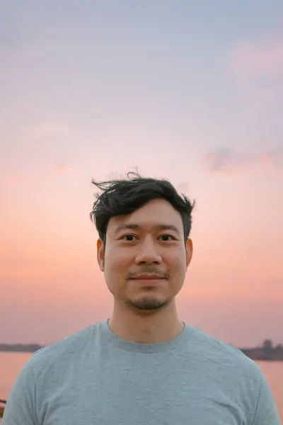 stock image Portrait of asian man standing with smooth colorful sunset sky.