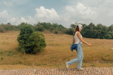 Neşeli Asyalı kadın dağların tepelerini ve tarlalarını gezmek için yürüyor..