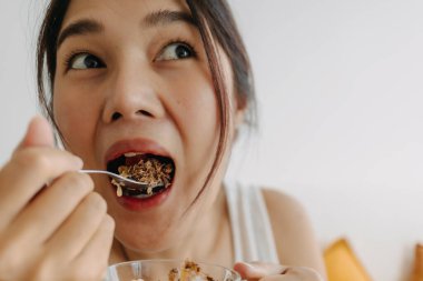 Yoğurttan tatlı yiyen Asyalı kadının yüzünün tadını çıkar. Sağlıklı beslenme.