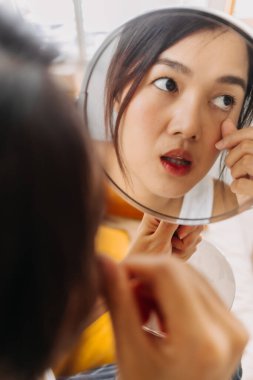 Makyaj aynası kullanan Asyalı kadın..