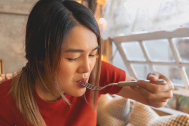 Kırmızılı Asyalı kadın güzelliğini önemsemeden fırın yiyor..