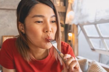 Kırmızılı Asyalı kadın güzelliğini önemsemeden fırın yiyor..