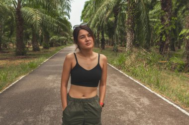 Kargo pantolonlu Asyalı kadın ve tropikal palmiye çiftliğinde kolsuz bluz..