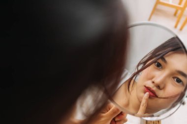 Makyaj aynası kullanan Asyalı kadın..