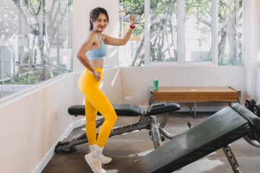 Asyalı kadın, spor salonundaki sarı mavi spor kıyafetlerinden etkilenmiş..