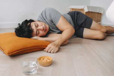 Asyalı bir adamın yerde kestirirken düşük açılı görüntüsü hafta sonu dinlenir..