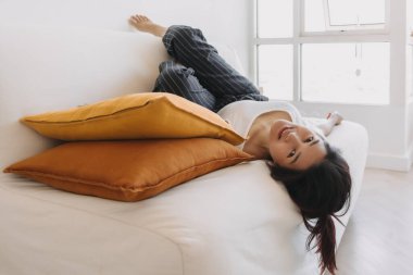 Hafta sonları hayat sıkıcı olduğu için Asyalı kadın oturma odasındaki kanepede uzanıyor..