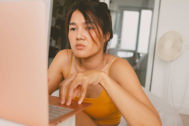 Laptop bilgisayarıyla çalışan Asyalı kadın evden sıkıcı işler yapıyor..