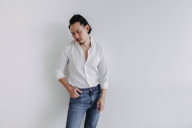 Üzgün surat, uzun saçlı, beyaz gömlekli Asyalı adam çöreği ve beyaz kot pantolon..