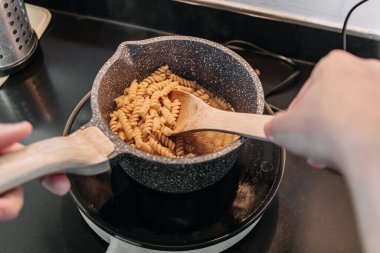 Asyalı adam küçük dairesinde ev yapımı makarna pişiriyor..