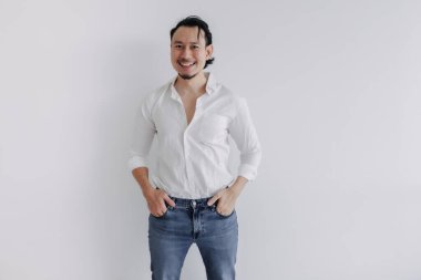 Gülen surat, uzun saçlı Asyalı, beyaz gömlekli, kot pantolonlu beyaz adam..
