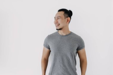 Gülümsemek için iyi bir poz. Gri tişörtlü Asyalı adam beyazları soyutladı..