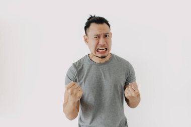 Gri tişörtlü Asyalı 'nın öfkeli ve öfkeli yüzü beyazı izole ediyor..