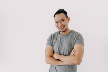 Gülümsemek için iyi bir poz. Gri tişörtlü Asyalı adam beyazları soyutladı..
