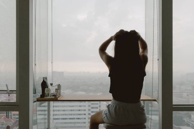 Asyalı kadın penceresinde dinleniyor, manzaranın ve zamanın tadını çıkarıyor..