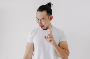 Gizli ipuçlarını bilmenin komik gülüşü beyaz tişörtlü Asyalı adamı gösteriyor..