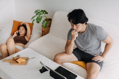 Asyalı çift aşığı, kadın telefondayken evde çalışan bir erkek..