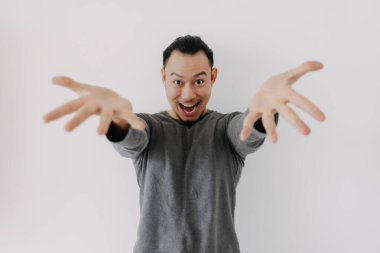 Gri yün katmanlı Asyalı adam beyazdan sunar..