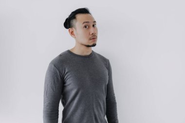 Gri yün katmanlı Asyalı adamın beyazın üzerinde durduğunu düşünüyor..