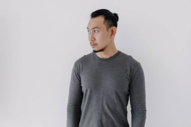 Gri yün katmanlı Asyalı adamın beyazın üzerinde durduğunu düşünüyor..