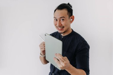 Kulaklıklı Asyalı Mutlu Yaratıcı Serbest Asyalı adam tabletle çalışıyor. Beyazları ayır.