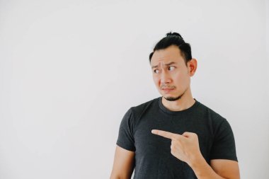 Üzgün ve hayal kırıklığına uğramış Asyalı bir adam. El işaretli, siyah tişörtlü, beyaz tenli..