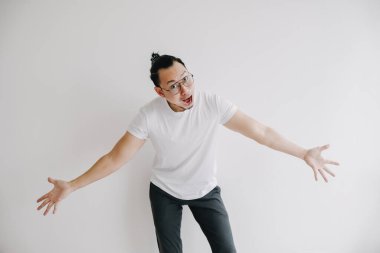 Beyaz arka planda kolları açık, gözlüklü, heyecanlı Asyalı genç adam..