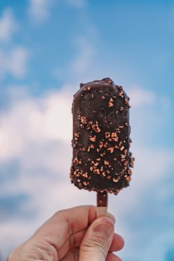 Plaj masmavi arka planında çikolatalı dondurma çubuğu.