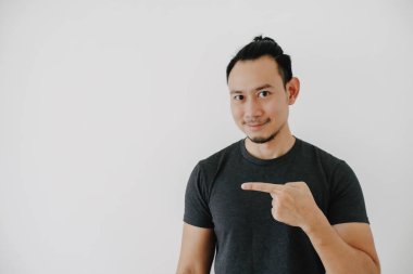 Mutlu gülümseme Asyalı adam eli işaret eden siyah tişörtlü beyaz tişörtlü..