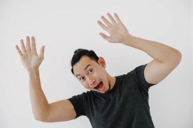 Neşeli Asyalı adam siyah tişörtle selam vermek için el sallıyor..