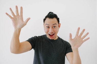 Neşeli Asyalı adam siyah tişörtle selam vermek için el sallıyor..