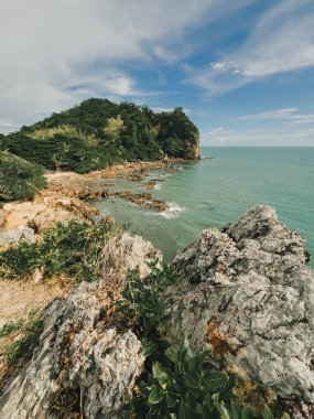 Güneşli gökyüzünün altında kayalık kıyı şeridi ve mavi tropikal deniz manzarası