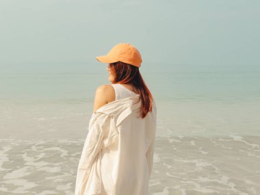 Asyalı kadın güneşli bir günde kumsalda güneşli bir suyla rahatladı, Tayland.