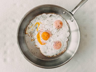Protein yemeği, paslanmaz tavada pembe tuz ve biberli kızarmış yumurta..