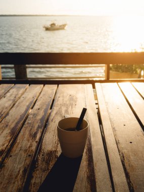 Gün batımında okyanusun kıyısındaki kırsal güvertede en az kahve fincanı.