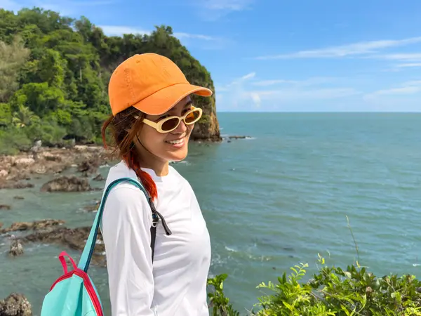 Turist tropikal ortamda açık mavi gökyüzü altında kıyı manzarasının tadını çıkarıyor