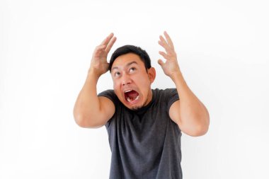 Komik Asyalı adam korkunç bir yüz ifadesi takınıyor ve beyaz arka planda soyutlanmış gibi davranıyor..