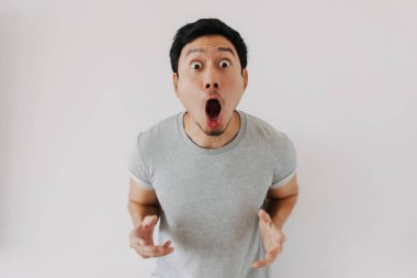Genç Asyalı erkek abartılı yüz ifadesiyle yoğun bir şaşkınlık gösteriyor.