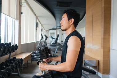 Güç makinesiyle içeride çalışan kaslı bir erkeğin yan görüntüsü